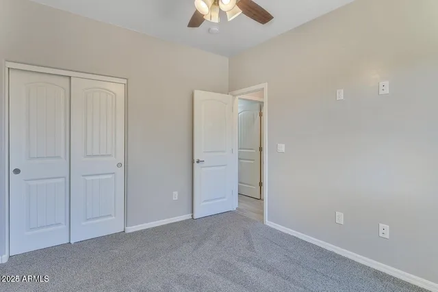 a view of an empty room and chandelier fan