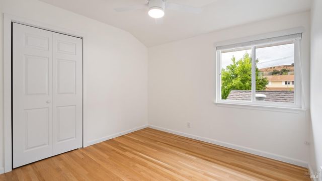a view of empty room with wooden floor and fan
