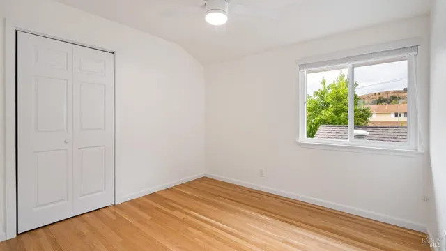 a view of empty room with wooden floor and fan