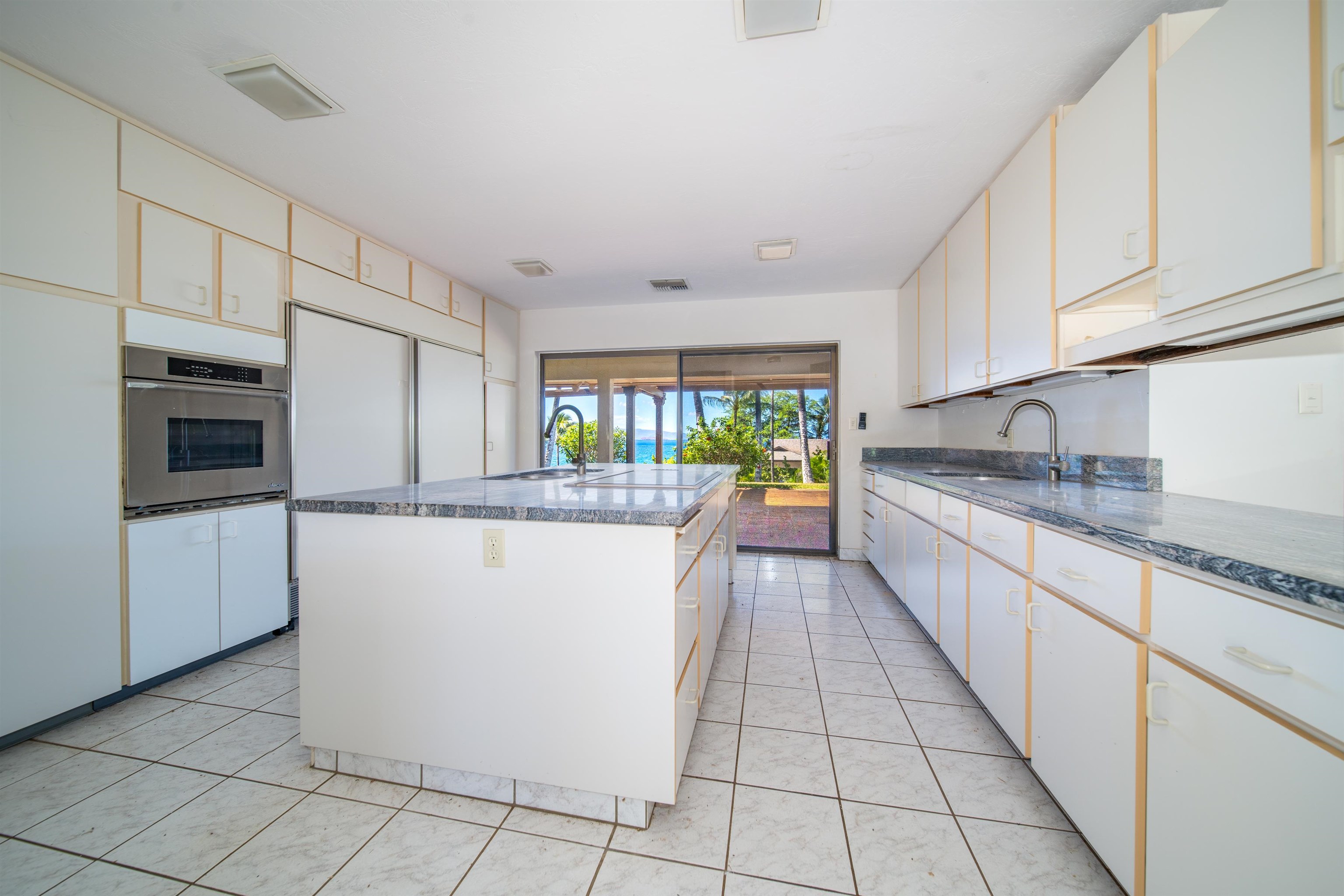 4584 Makena Road Kihei, HI 96753 - Photo 22 of 30 a kitchen with stainless steel appliances granite countertop a refrigerator a sink dishwasher and white cabinets with wooden floor