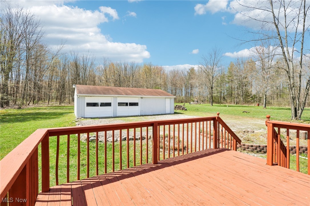 8307 Slagle Road Windham, OH 44288 - Photo 34 of 39 Wooden deck with an outdoor structure, a lawn, a garage, and a wooded view