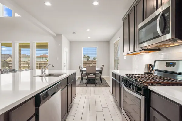 a kitchen with stainless steel appliances granite countertop a stove a sink and a microwave