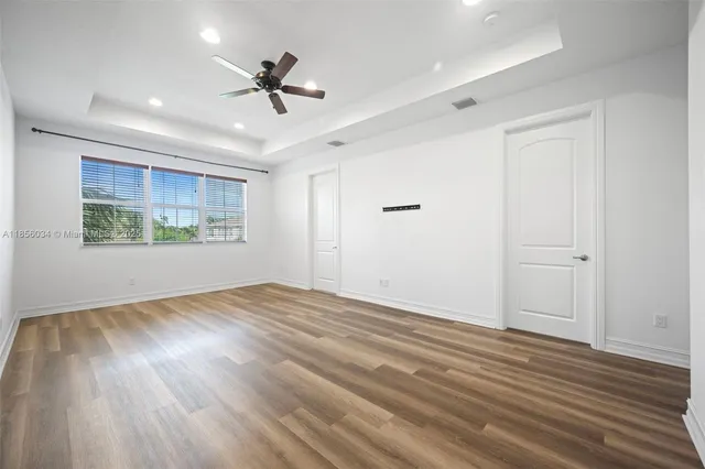 a view of an empty room with a window and wooden floor