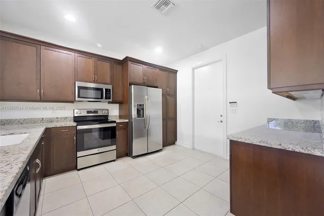 a kitchen with granite countertop a refrigerator and a stove top oven