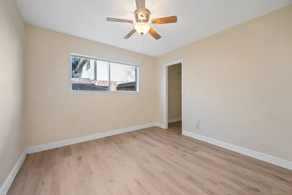 an empty room with windows and fan