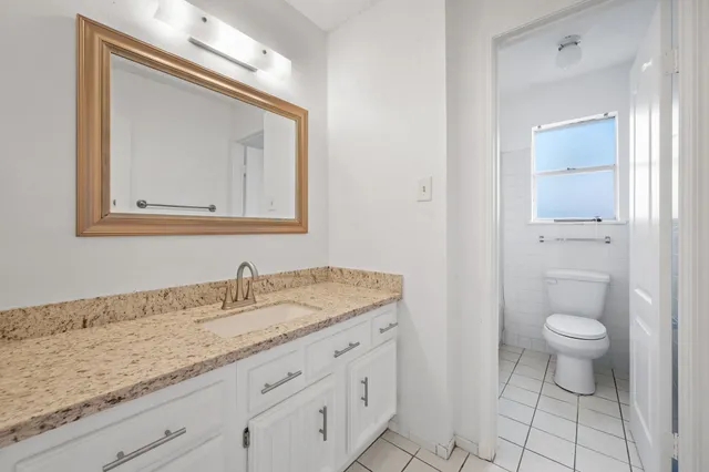 a bathroom with a granite countertop sink a toilet and a mirror