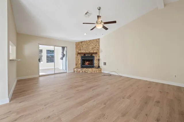 a view of empty room with wooden floor fireplace and fan