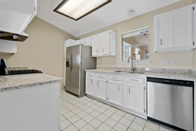 a kitchen with granite countertop white cabinets and refrigerator