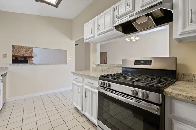a kitchen with granite countertop a stove and a white cabinets