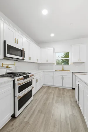 a kitchen with granite countertop white cabinets and stainless steel appliances
