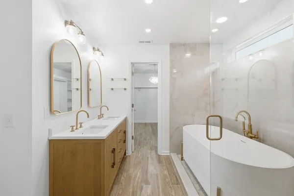 a spacious bathroom with a double vanity sink a large mirror and shower