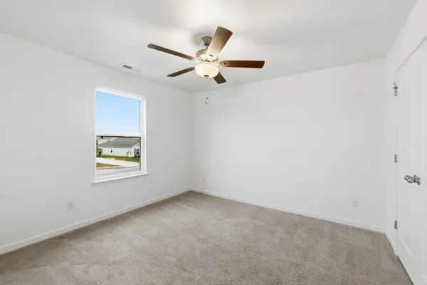 an empty room with ceiling fan and window