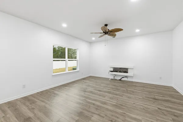 a view of an empty room with a window and a ceiling fan