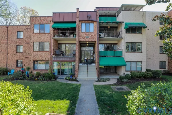 a view of a brick building with many windows and a yard