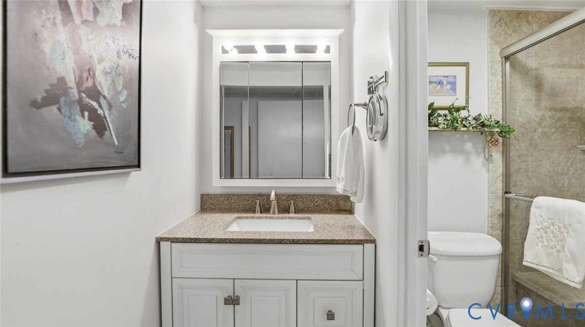 1513 Regency Woods Road, Unit 101 Henrico, VA 23238 - Photo 26 of 50 a bathroom with a granite countertop sink a toilet and a mirror
