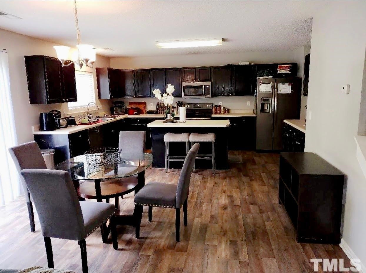 6041 Ricker Road Raleigh, NC 27610 - Photo 8 of 20 a dining room with stainless steel appliances kitchen island granite countertop a table chairs and a microwave