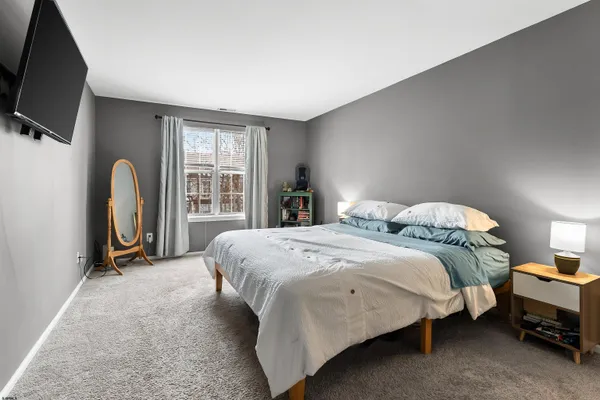 a bedroom with a bed a flat screen tv and dresser