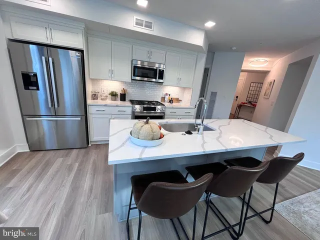 a kitchen with refrigerator and wooden floor