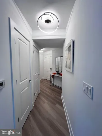 a view of a hallway with wooden floor and a bathroom