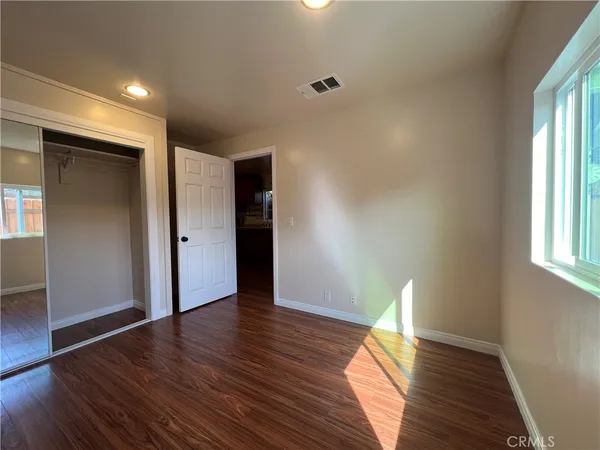 a view of empty room with wooden floor and window
