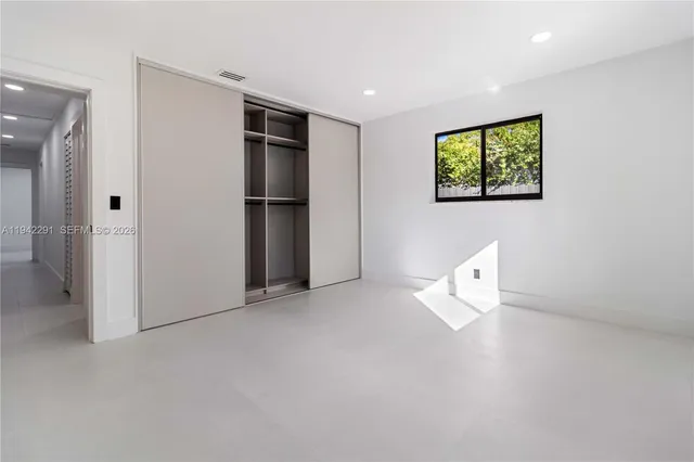 an empty room with closet and windows