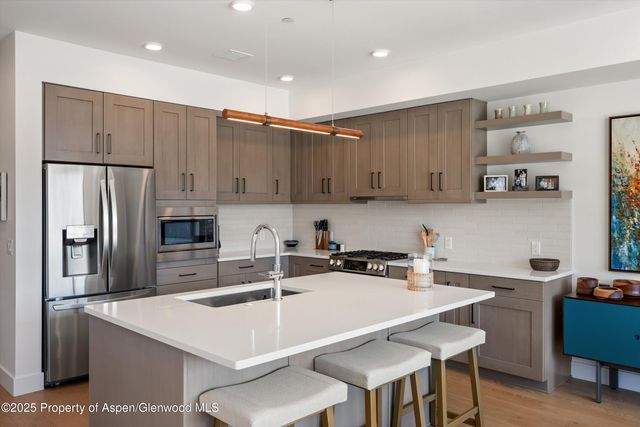 a kitchen with stainless steel appliances a table chairs refrigerator and microwave