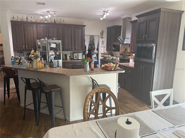 a kitchen with stainless steel appliances granite countertop a table chairs and a refrigerator