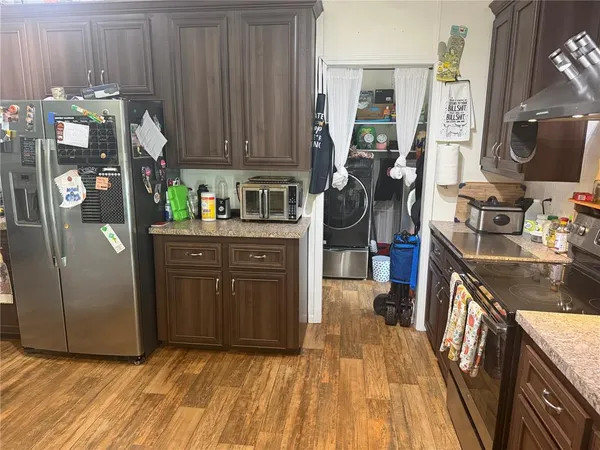 a kitchen with stainless steel appliances granite countertop a refrigerator a stove and a wooden cabinets