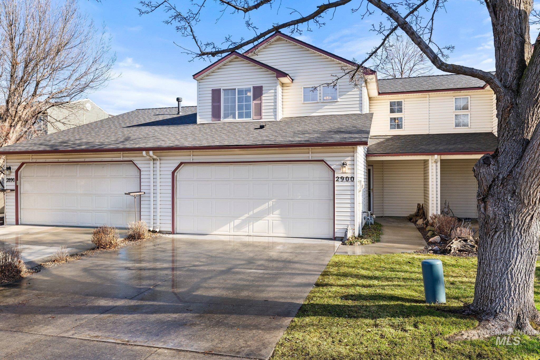 Traditional-style house with roof with shingles, driveway, a garage, and a front lawn