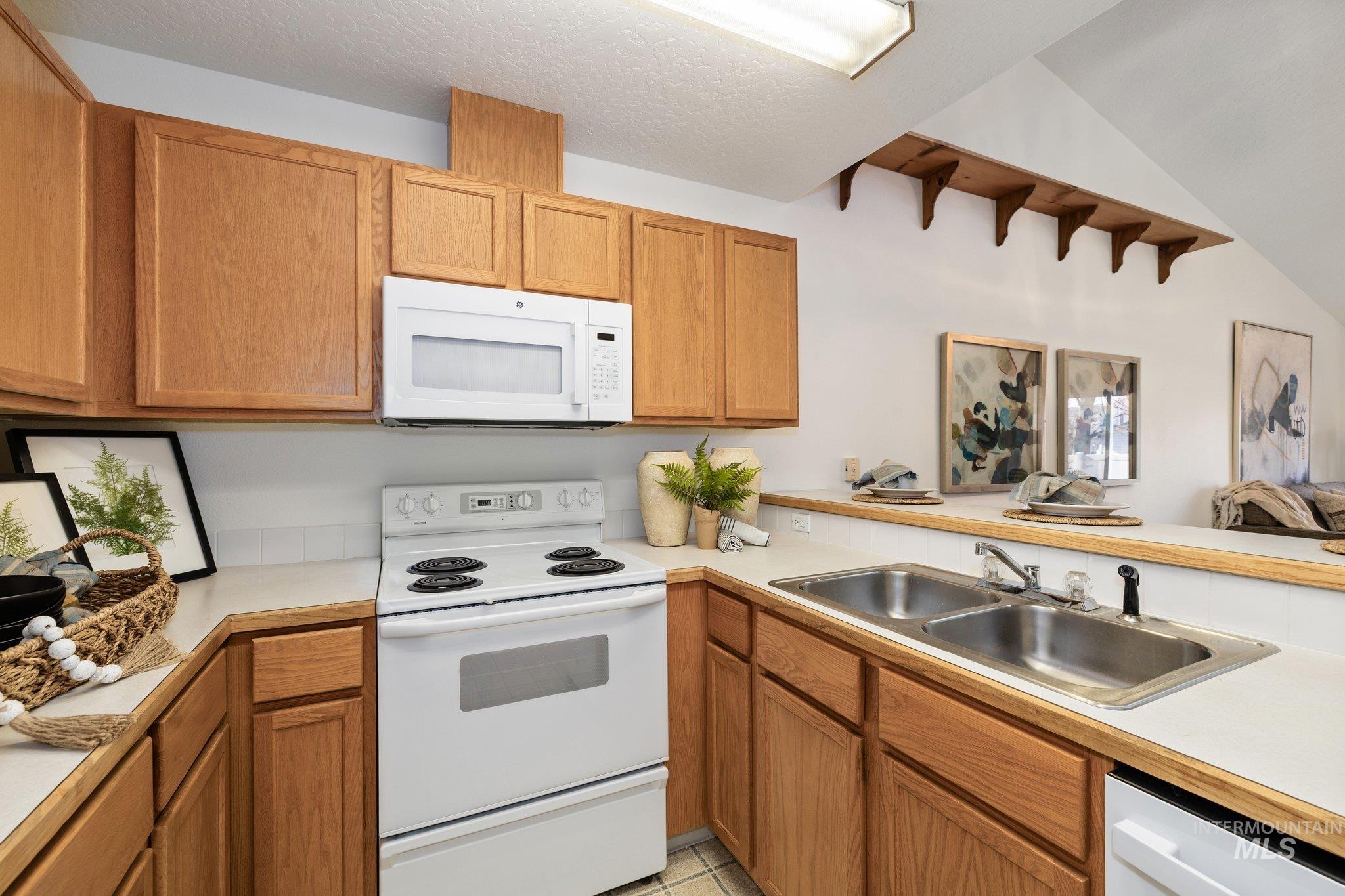 2900 South Ladera Place Boise, ID 83705 - Photo 12 of 31 Kitchen with white appliances, light countertops, brown cabinetry, and vaulted ceiling