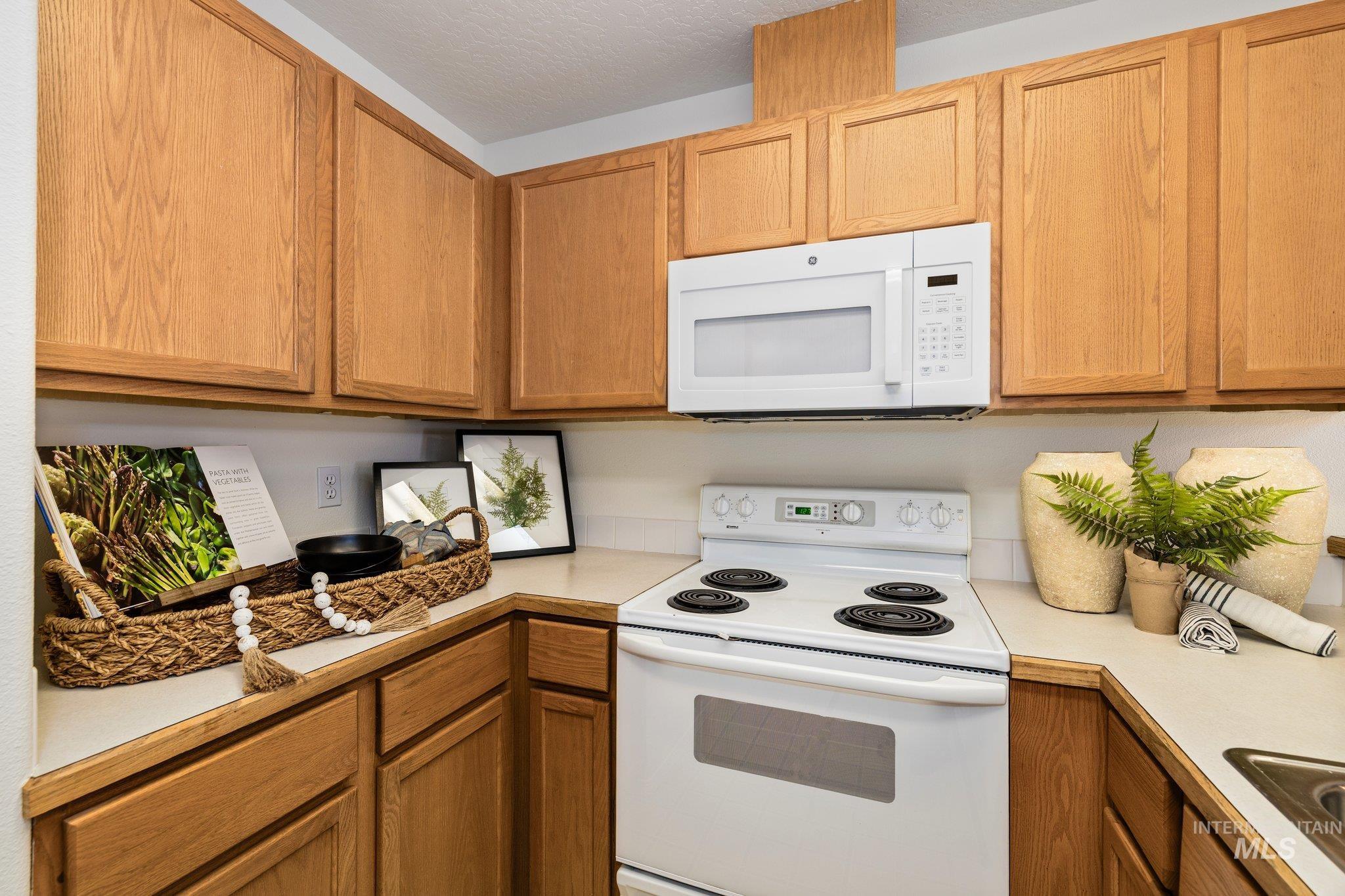 2900 South Ladera Place Boise, ID 83705 - Photo 13 of 31 Kitchen featuring white appliances, light countertops, and brown cabinetry