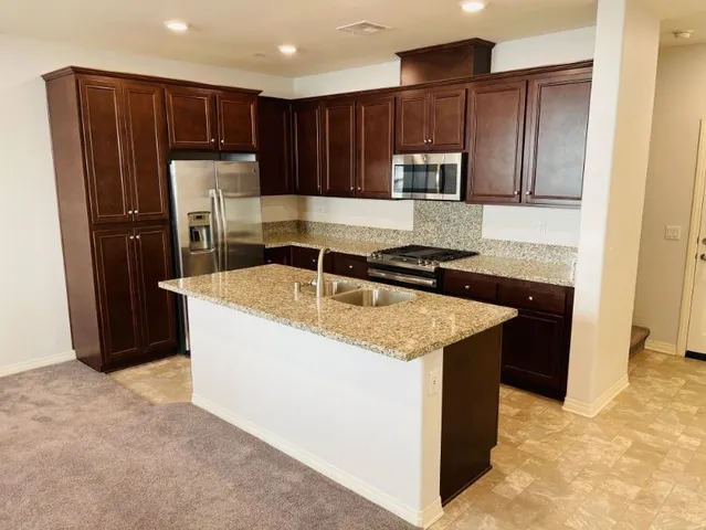 a kitchen with granite countertop a refrigerator and a sink