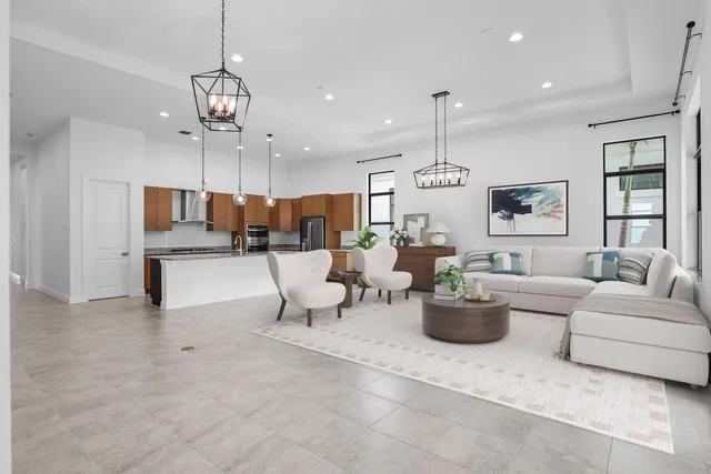 a living room with furniture kitchen view and a chandelier