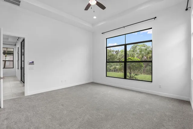 an empty room with chandelier fan and windows