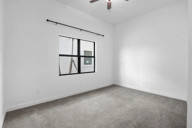 an empty room with windows and fan