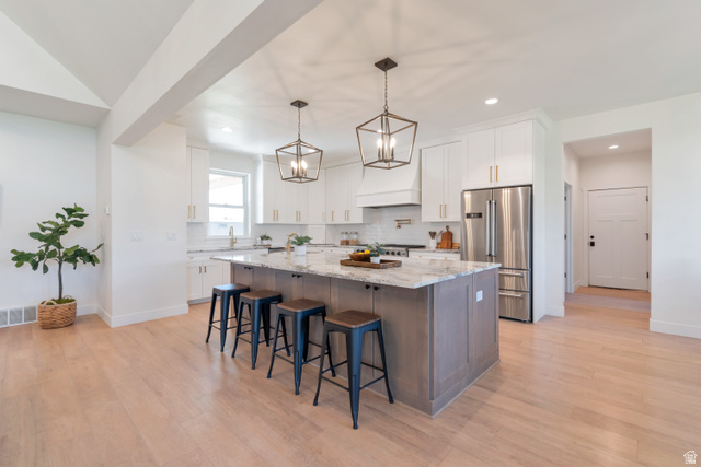 1820 West Farmhouse Flats Road Peoa, UT 84061 - Photo 16 of 79 Expansive kitchen featuring a large central island with seating, white cabinetry, integrated stainless steel appliances, and wood-finish flooring