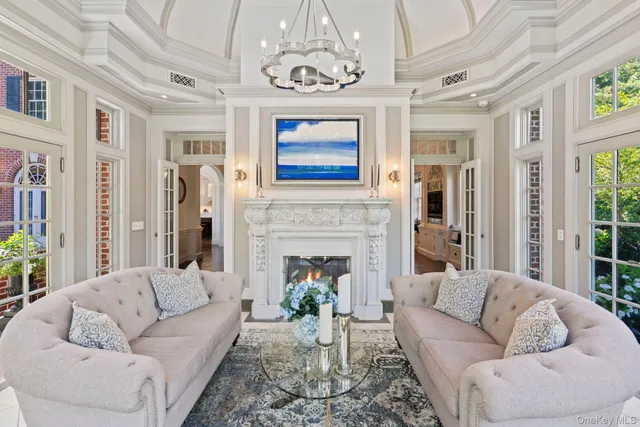 a living room with furniture a fireplace and a chandelier