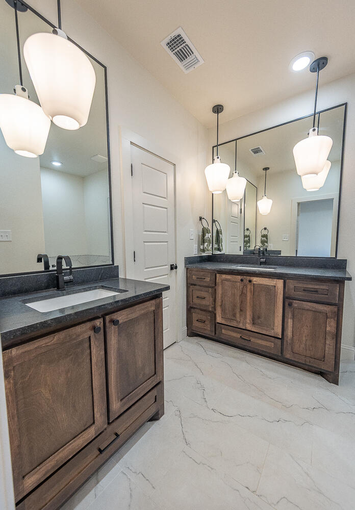 3605 143rd Street Lubbock, TX 79423 - Photo 16 of 34 a bathroom with a double vanity sink and a mirror
