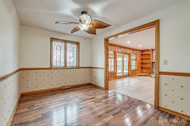 an empty room with wooden floor fan and windows