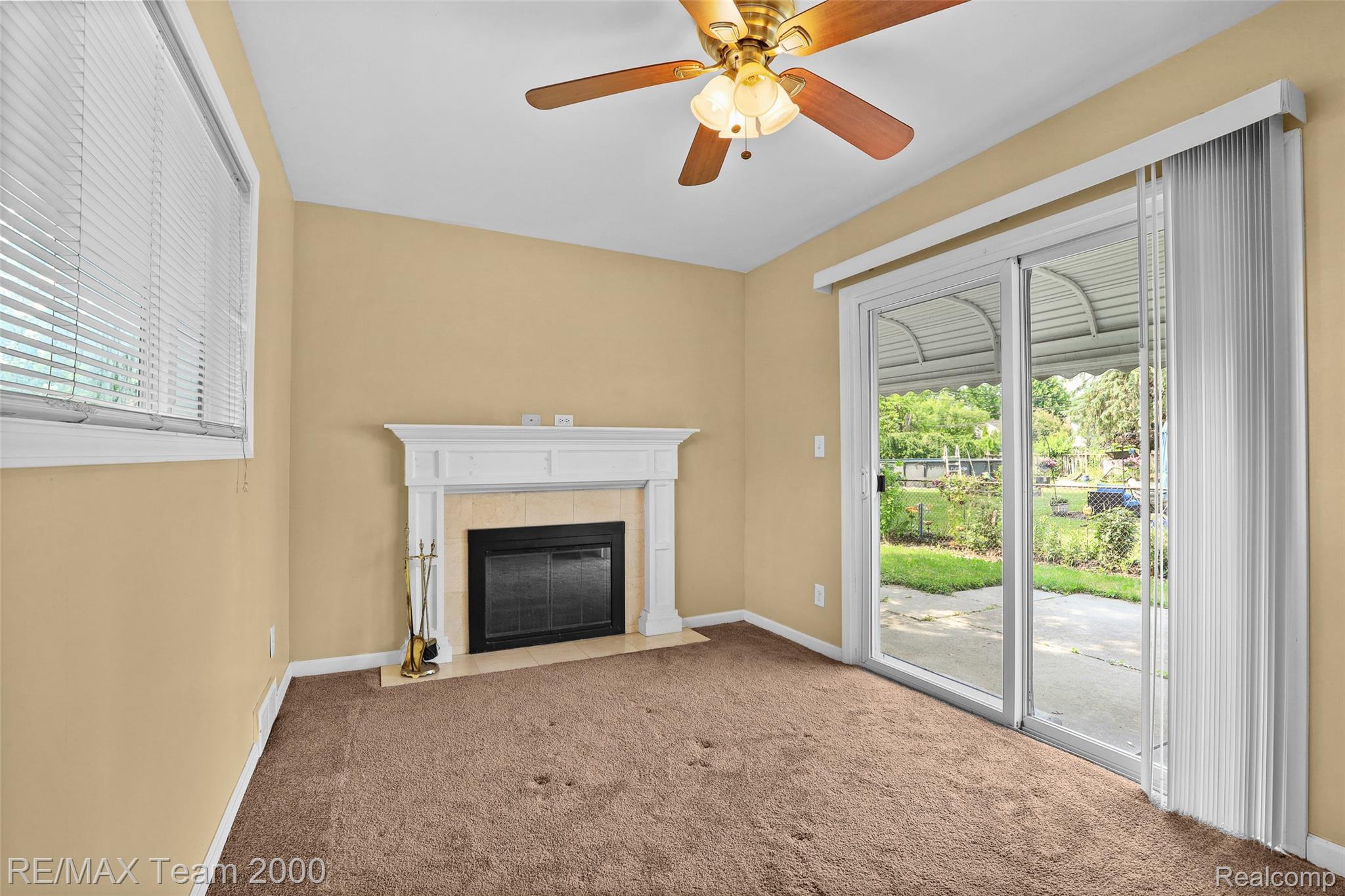 3130 Chestnut Street Dearborn, MI 48124 - Photo 10 of 30 Living area featuring a white mantel fireplace, sliding glass door with vertical blinds, and a window with horizontal blinds