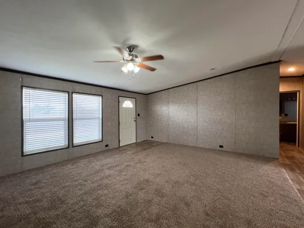 an empty room with chandelier fan and windows