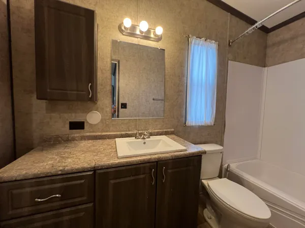 a bathroom with a granite countertop sink toilet a mirror and shower