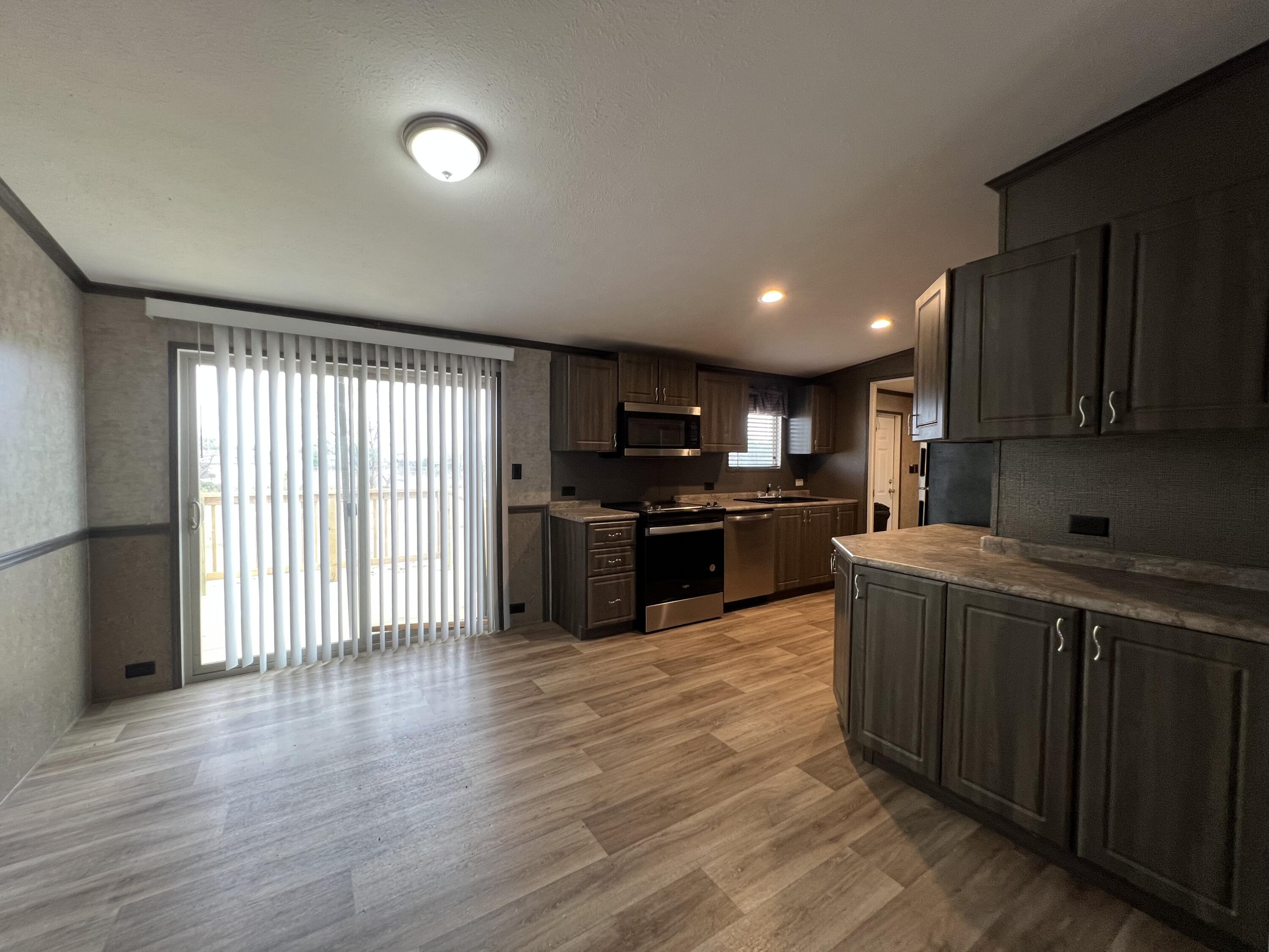 516 May Street Post, TX 79356 - Photo 7 of 31 a kitchen with stainless steel appliances granite countertop a stove top oven a sink with wooden floors and cabinets