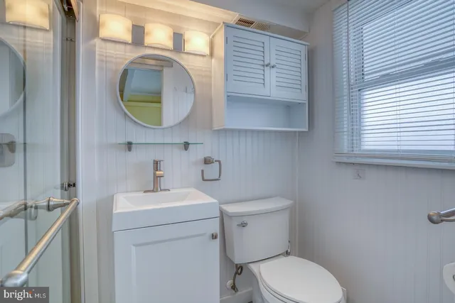 a bathroom with a toilet sink vanity and mirror