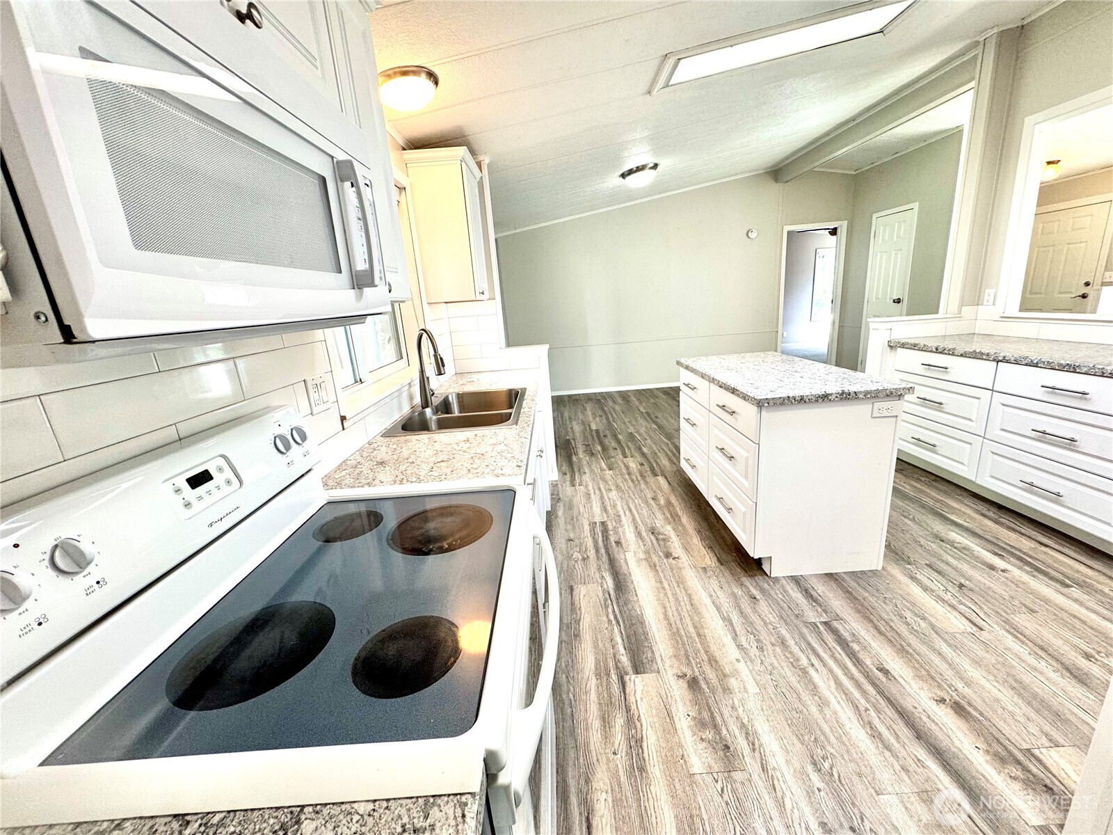 1218 South 3rd Street Dayton, WA 99328 - Photo 12 of 23 a kitchen with a sink and a stove next to a white cabinet with wooden floor