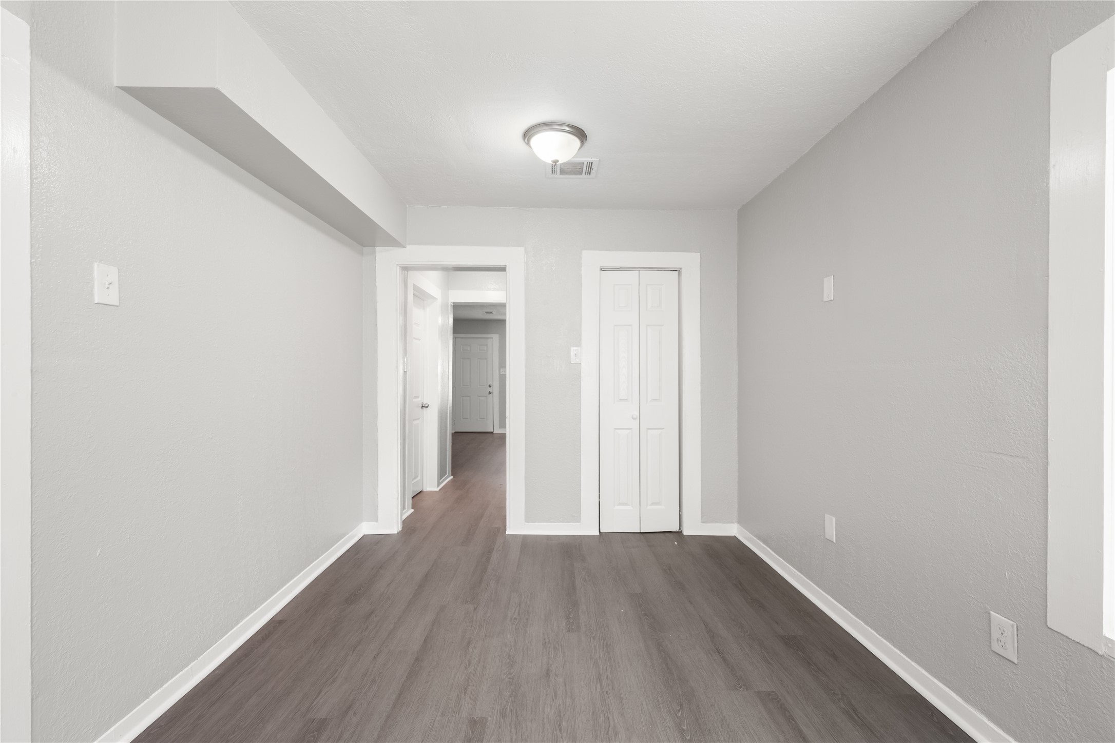 9210 Compton Street Houston, TX 77016 - Photo 13 of 50 Bright and spacious room with modern vinyl flooring and neutral gray walls, providing a versatile space for customization.