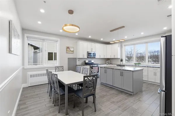 a kitchen with a dining table chairs cabinets wooden floor and appliances