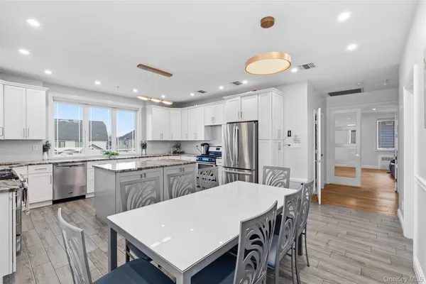 a kitchen with stainless steel appliances granite countertop a kitchen island a stove a table and a refrigerator