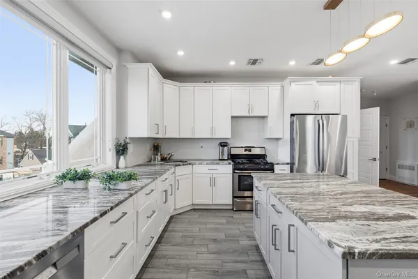 a large kitchen with stainless steel appliances granite countertop a stove a sink and a refrigerator