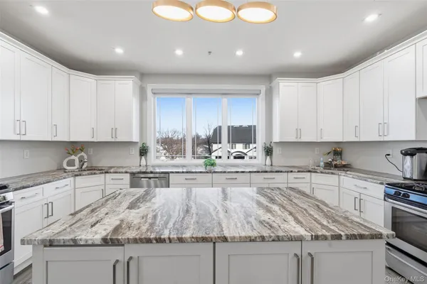 a kitchen with kitchen island granite countertop a sink a stove and cabinets
